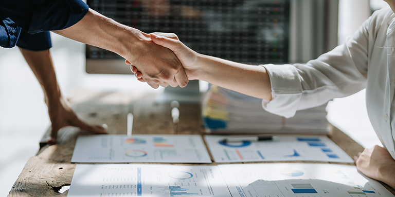 two people shaking hands over a table