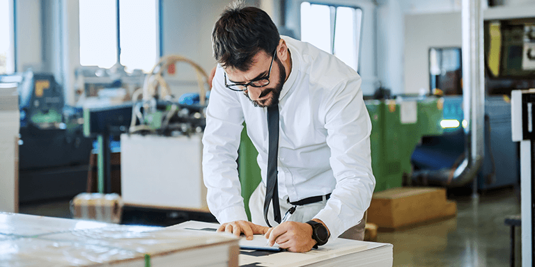 man standing at a table writing on paper