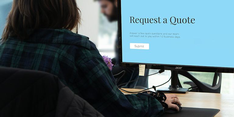 woman working on a computer at a desk with request a quote on the monitor