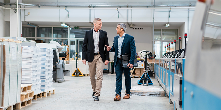 Two men in the print industry walking and talking about business