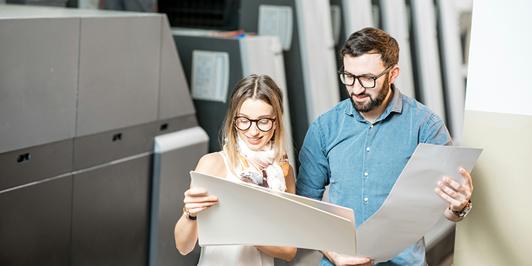 Printers looking at a printed piece together