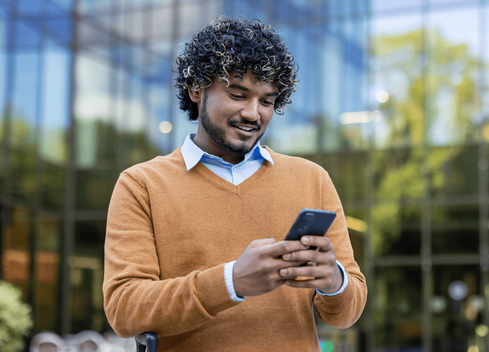 Middle-aged man looking at his cell phone while outside in a city